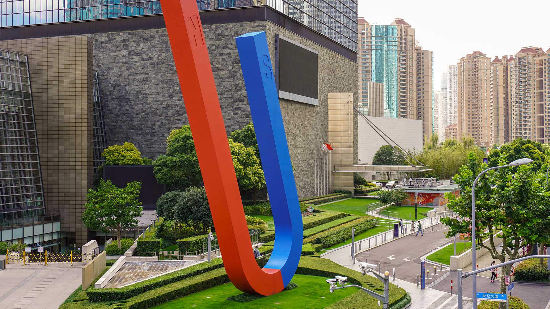 A large magnet sculpture placed on a lawn in front of an office building. 