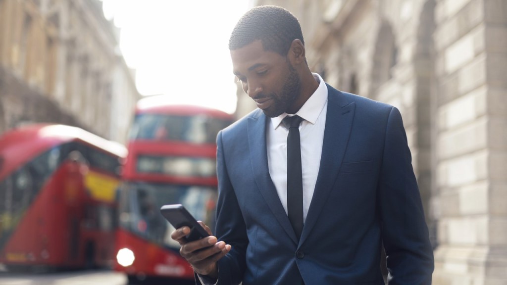 A male traveler is using messaging on their mobile device